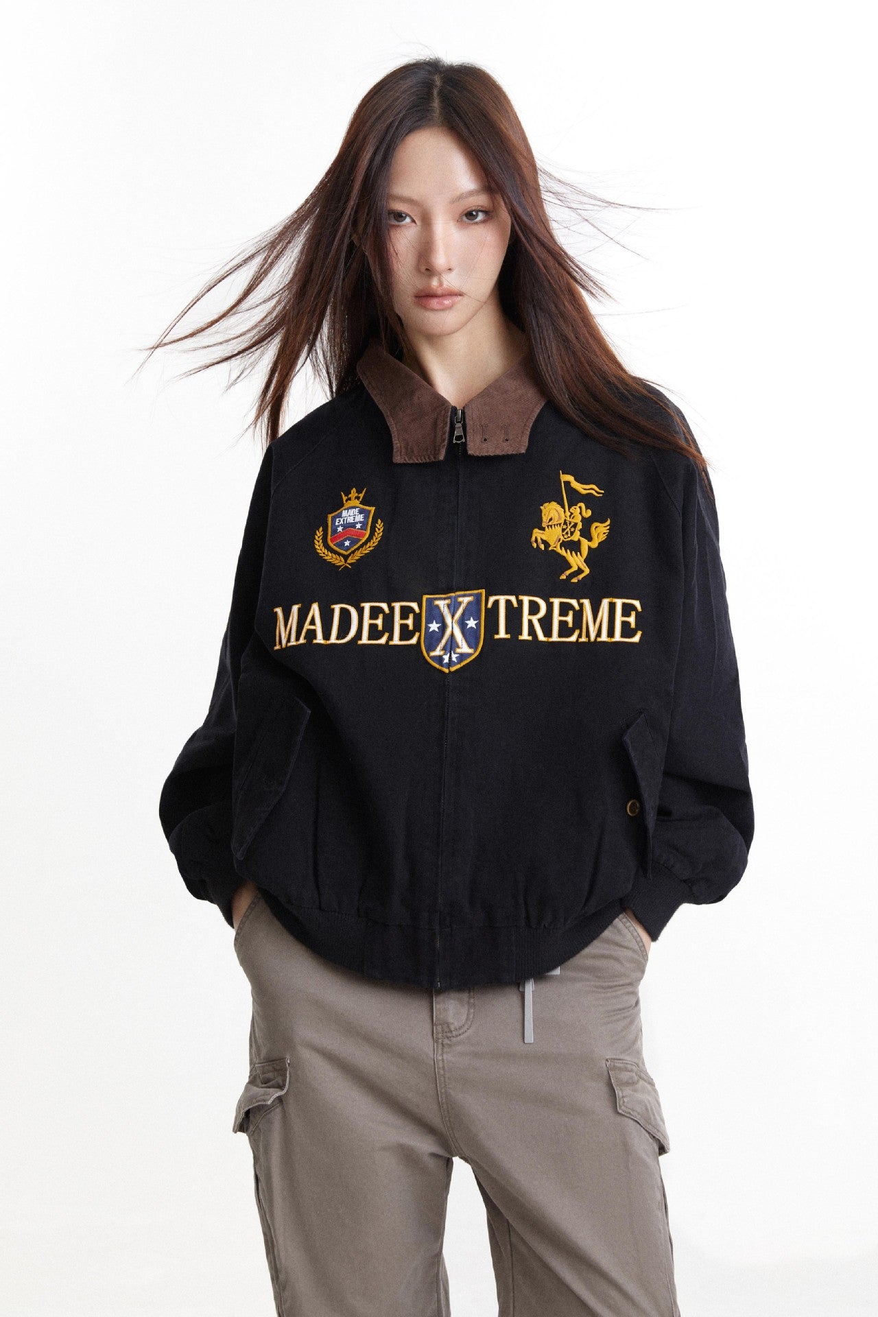 Close front view of black embroidered jacket with crest and equestrian graphics