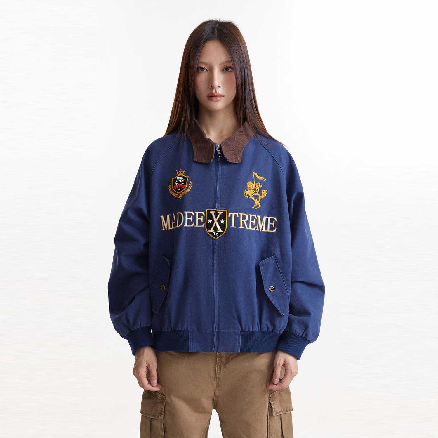 Front studio view of blue jacket with crest embroidery and flap pockets