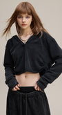 Black cropped hoodie, front view—drop shoulder and rib cuffs.