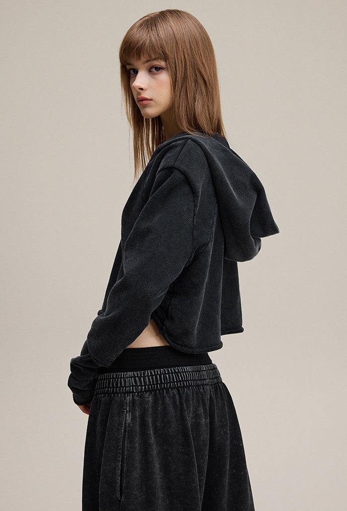 Black cropped hoodie, side view—drop shoulder and rib cuffs.