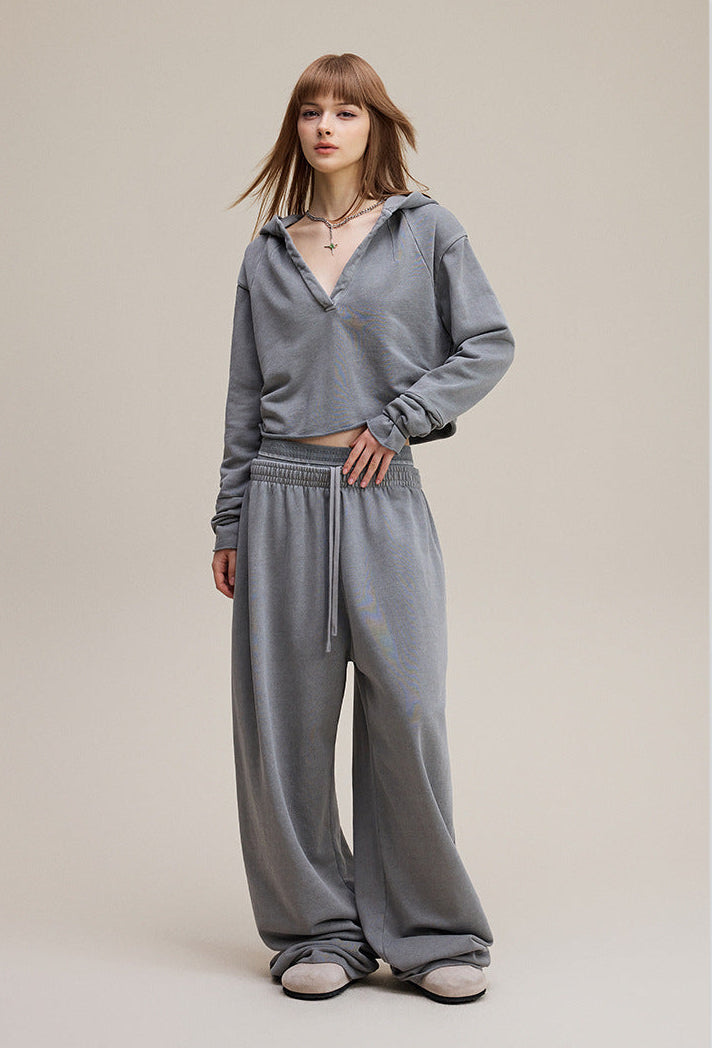 Model front view wearing light gray cropped hoodie with raw hem and drop shoulder.