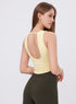 Back view of woman in custard workout tank top and olive green high-waist leggings.