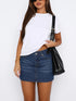 Model wearing a white t-shirt tucked into a dark blue denim mini skirt with a black shoulder bag.