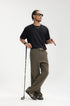 Model in dark brown mens dress pants holding golf club, casual smart look