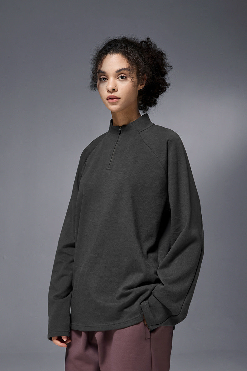 Person wearing a dark gray half-zip long-sleeve tshirt against a gray background