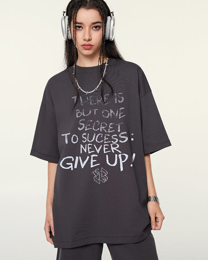 Female model in dark purple graphic T-shirt and shorts standing confidently with headphones and minimal accessories.