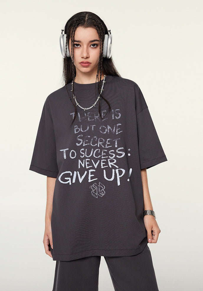 Female model in dark purple graphic T-shirt and shorts standing confidently with headphones and minimal accessories.