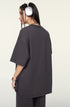 Side view of female model in dark purple oversized T-shirt and shorts, turning to reveal back.