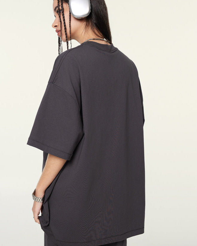 Side view of female model in dark purple oversized T-shirt and shorts, turning to reveal back.