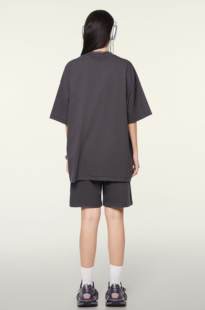 Rear view of model wearing dark purple oversized T-shirt and shorts, showing plain back design.