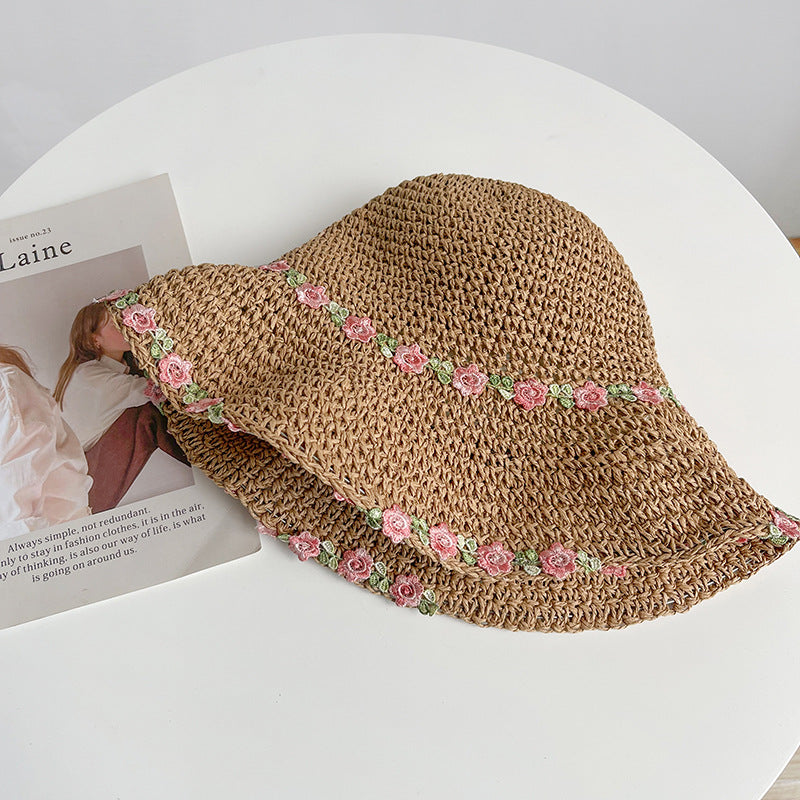  A foldable khaki straw hat featuring delicate pink floral embroidery, adding a soft, romantic charm to any summer outfit.