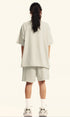 Rear view of model in off-white "Deserve" devil graphic tee and shorts.