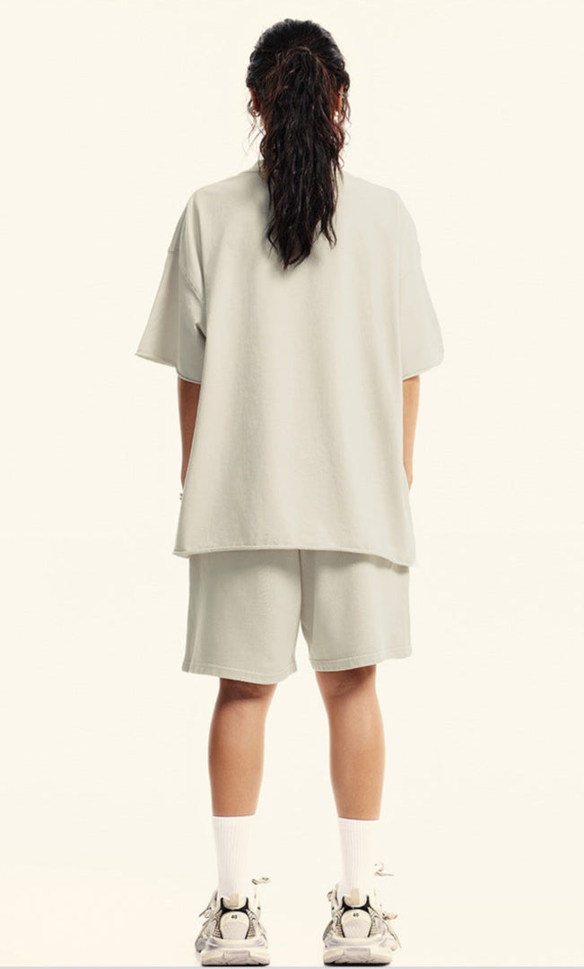 Rear view of model in off-white "Deserve" devil graphic tee and shorts.