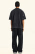 Rear view of black "Deserve" tee styled with wide-leg pants.