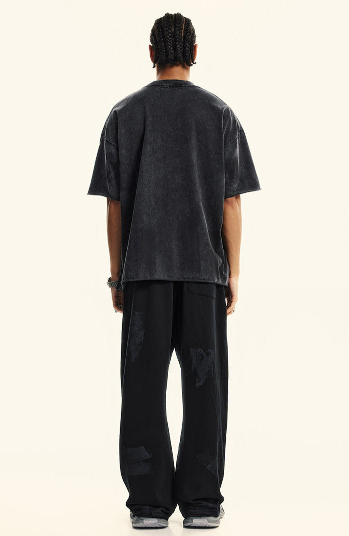 Rear view of black "Deserve" tee styled with wide-leg pants.