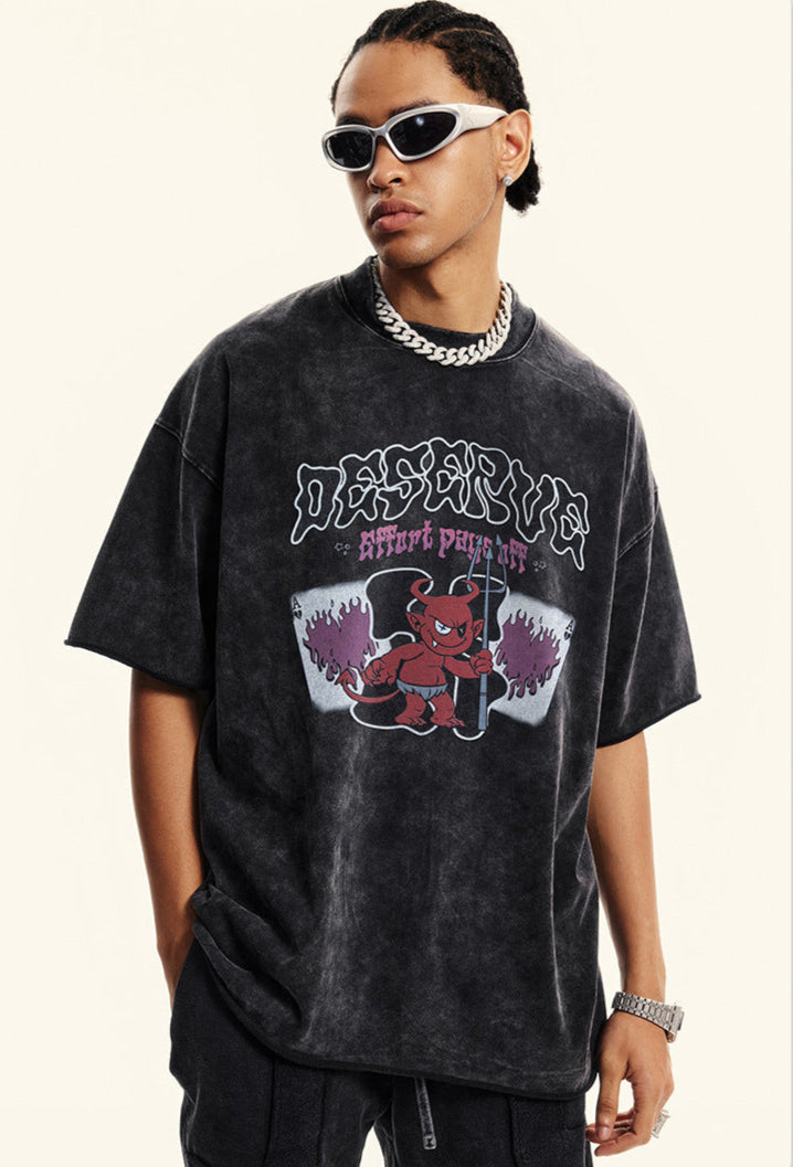 Man wears oversized black graphic tee with red devil and 'DESERVE' text.