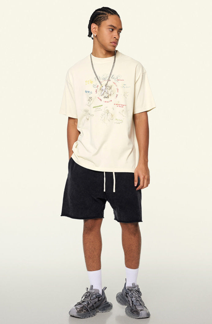 Model in cream colored graphic tee with black shorts, facing slightly sideways