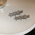 Silver hair clips with three sparkling rhinestone stars in a row, displayed on a white surface.

