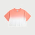 Coral and white ombré cropped short-sleeve t-shirt with gradual color fade from deep blue to white, featuring a crew neck and a small branded tag at the collar