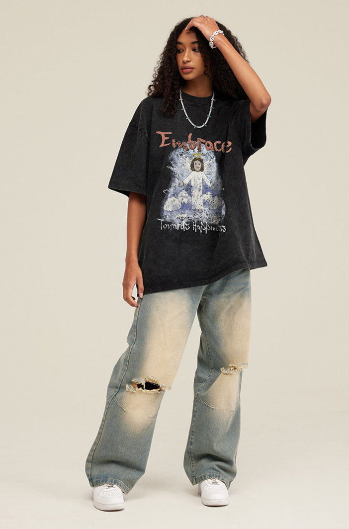 Model wearing black angel T-shirt and distressed jeans, tilting head and touching hair.