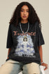 Model sitting while wearing black angel T-shirt, showing full print and necklace.