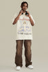 Model wearing cream angel graphic tee with headphones and brown cargo pants, standing pose.