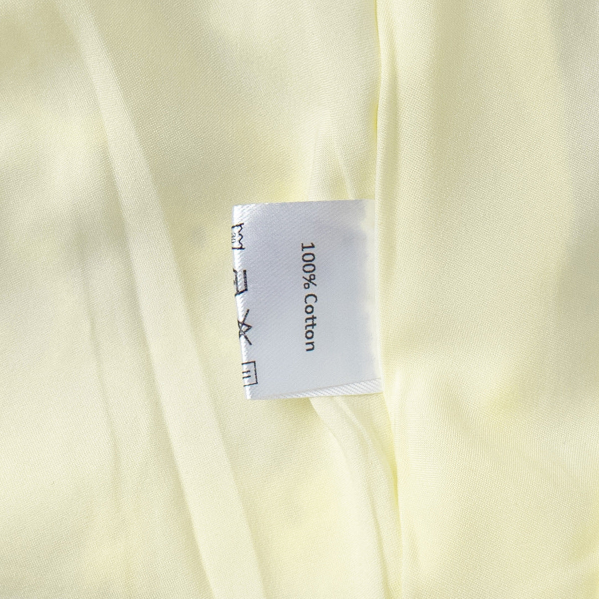 Label on a piece of light yellow fabric indicating 100% cotton.