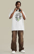 Model stands in white "Terrible Beauty" tee with green snake heart graphic.