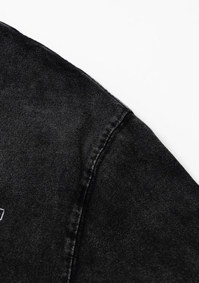 Close-up of shoulder seam stitching on black tee.