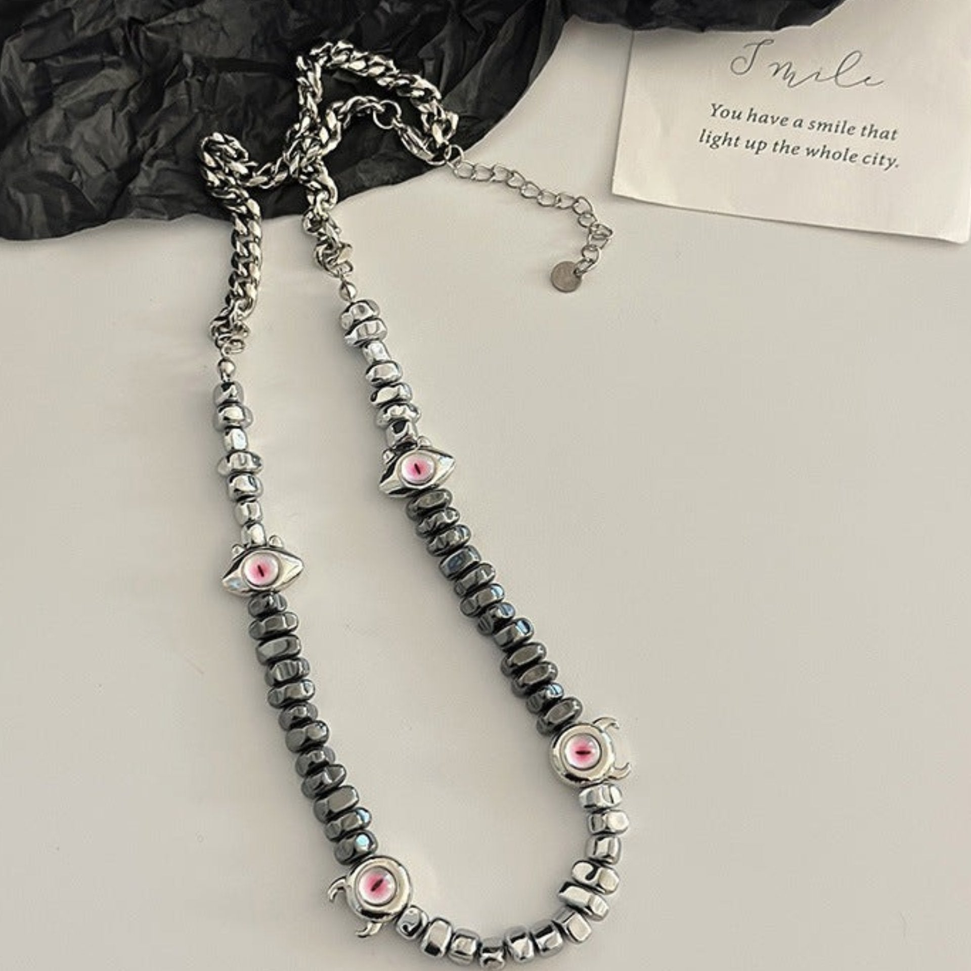 Beaded necklace with silver and black stones and pink evil eyes.