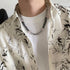Man wears black and silver evil eye necklace with beaded texture.
