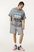 Model wearing grey Eyes Fade tee and shorts, looking down with hand in pocket.