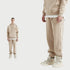 Beige sweatsuit showcased in split-view format with full outfit on left and close-up detail of jogger leg and designer sneaker on right against white background
