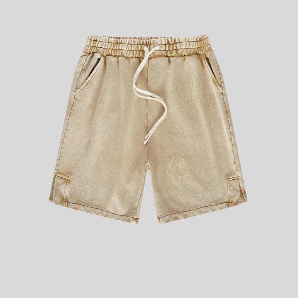 A pair of beige washed drawstring shorts featuring an elastic waistband, white drawstrings, and side pockets
