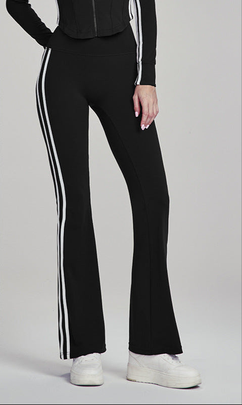 Woman in black flare leggings with white side stripes, standing at an angle.