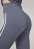 Woman modeling sea rock grey flare leggings with white stripes, close-up on hip seam.