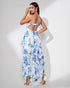Woman wearing a blue ruffle slit floral dress on a white background