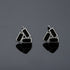 Pair of geometric black and silver colored stud earrings on glossy surface.