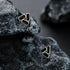 Geometric black stud earrings set on dark stone surface.