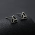 Geometric stud earrings displayed on textured black cylinder.