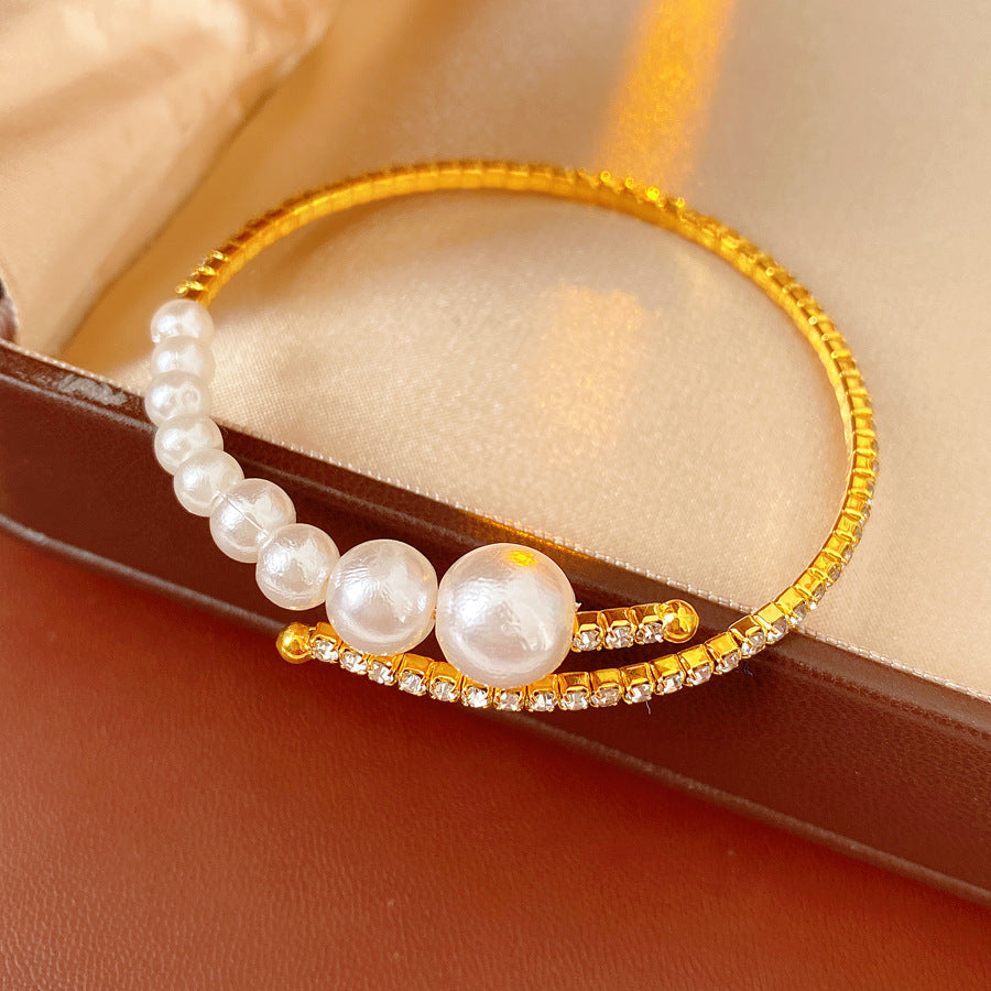 single gold pearl cuff bracelet placed on a warm beige surface