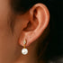 Gold pearl drop earring on ear, diamond-shaped stud, lightweight