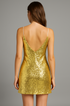 Back view of a gold sequin dress worn by a model on a gray background