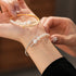 close-up of a hand wearing both the gold and silver pearl cuff bracelets together