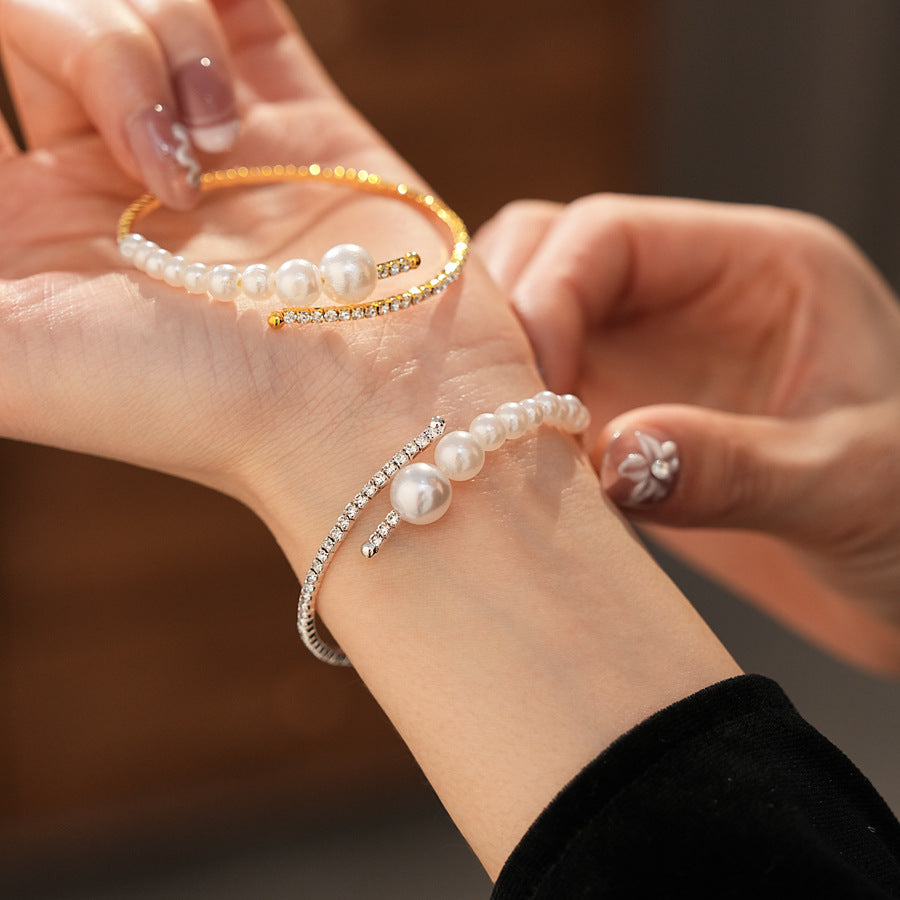 close-up of a hand wearing both the gold and silver pearl cuff bracelets together