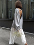 Side view of woman in gray backless knit sweater outdoors