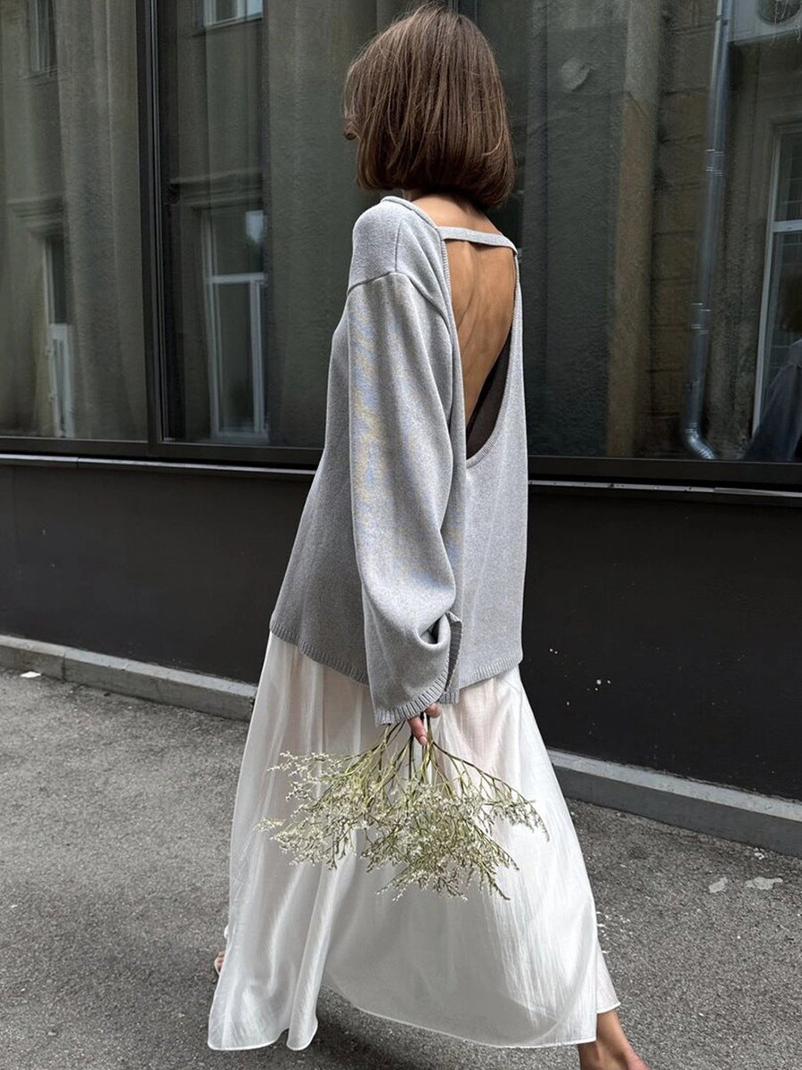Side view of woman in gray backless knit sweater outdoors