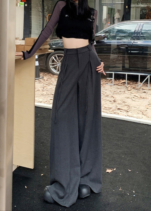 Model wearing gray flowy drawstring trousers styled with cropped ribbed sweater and beanie.