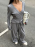 Person wearing a gray co ord set holding tumbler on a street.