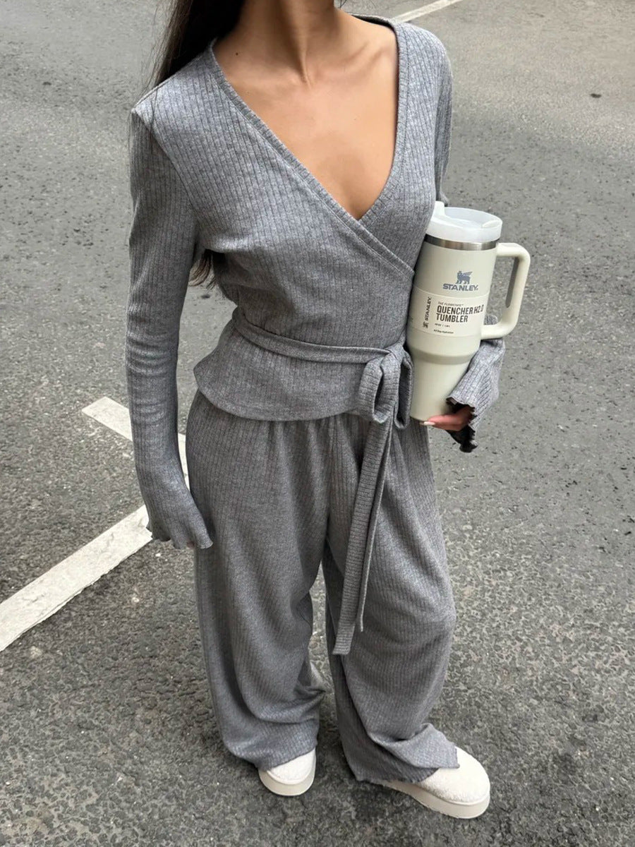 Person wearing a gray co ord set holding tumbler on a street.